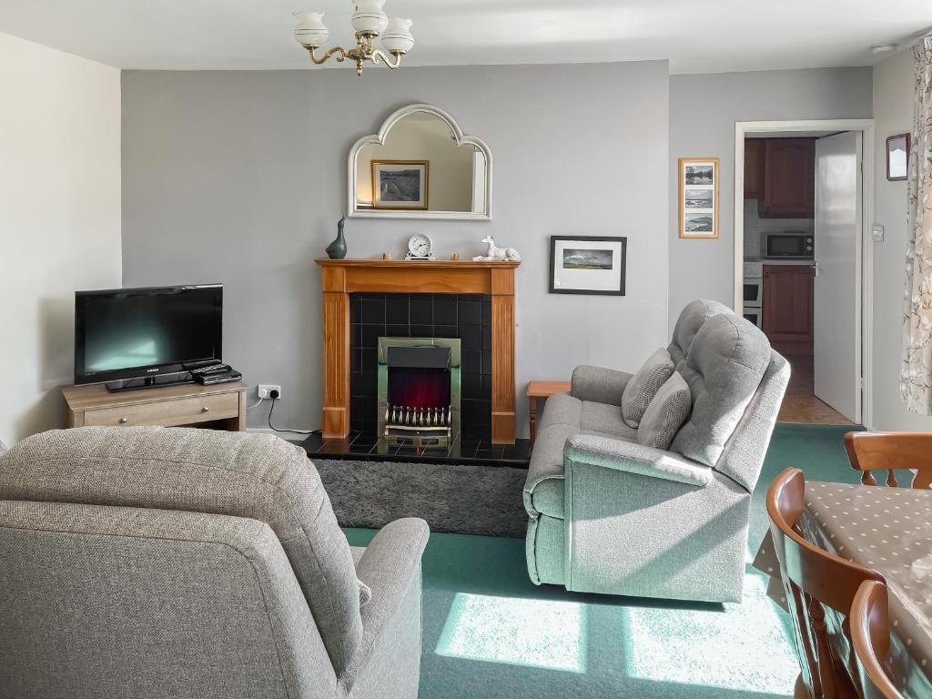 ein Wohnzimmer mit zwei Stühlen und einem Kamin in der Unterkunft Shepherd's Cottage - Uk48872 in Belford