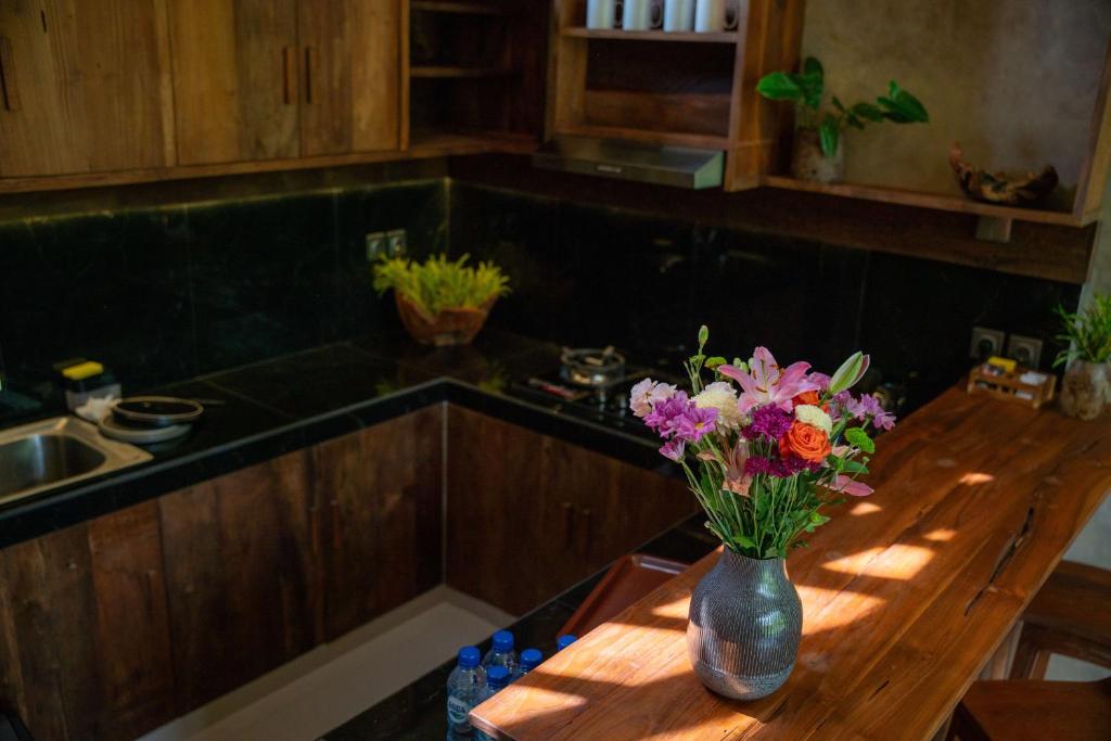 a vase of flowers sitting on a table in a kitchen at Elforest 3 in Payangan