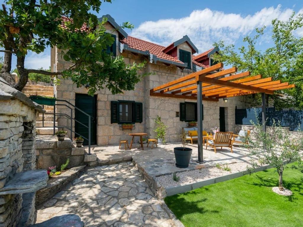 a patio with a wooden pergola in front of a house at Green Paradise with pool in Dropuljići