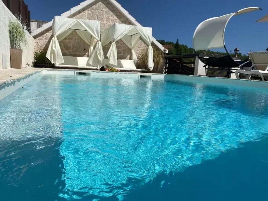 a large swimming pool with blue water in front of a house at Villa in Zagvozd with swimming pool in Vranješi