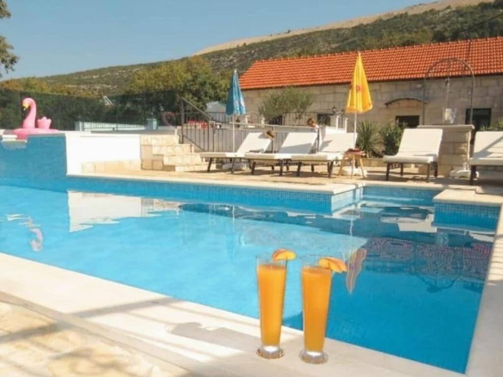 een zwembad met twee oranje drankjes in het water bij Villa in Zavojane with swimming pool in Vodenjak
