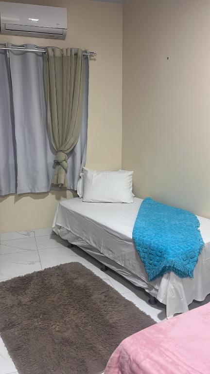 a bedroom with a bed with a blue blanket at Quarto em Belém - Próximo ao Mercado de São Brás in Belém