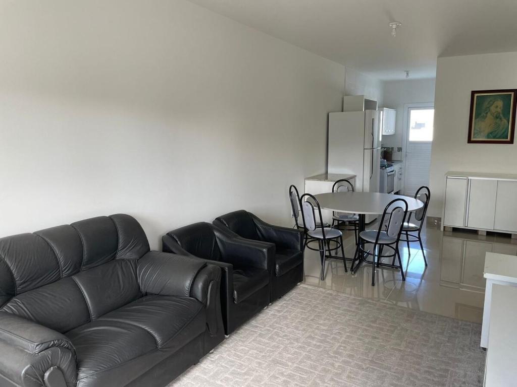 ein Wohnzimmer mit einer Ledercouch und einem Tisch in der Unterkunft Casa nova para alugar no bairro zona norte in Capão da Canoa