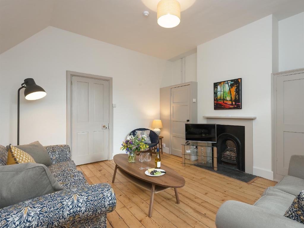 a living room with a couch and a table and a fireplace at Stable Yard Cottage in Selborne