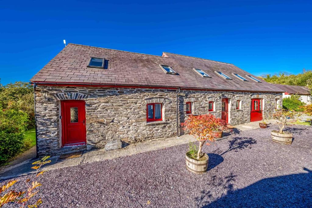 a stone house with red doors and potted plants at Gwyddfid-Y-Ffynnon in Llanfyrnach