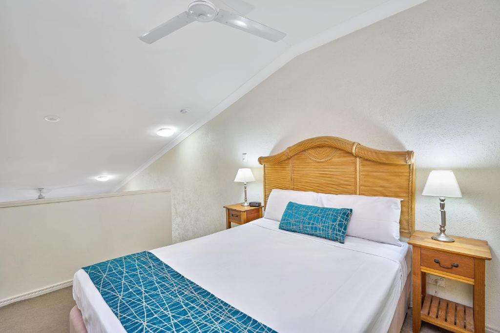 a bedroom with a large bed with a blue pillow at Trinity Beach Club Holiday Apartments in Trinity Beach