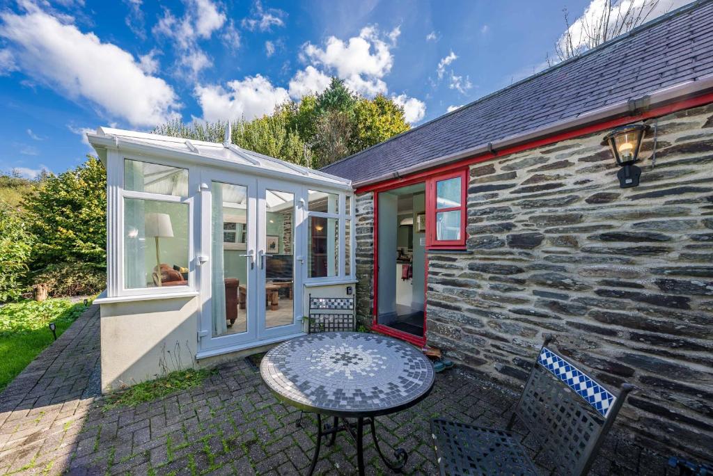 a stone house with a table and chairs on a patio at Eiddew-Y-Ffynnon in Llanfyrnach