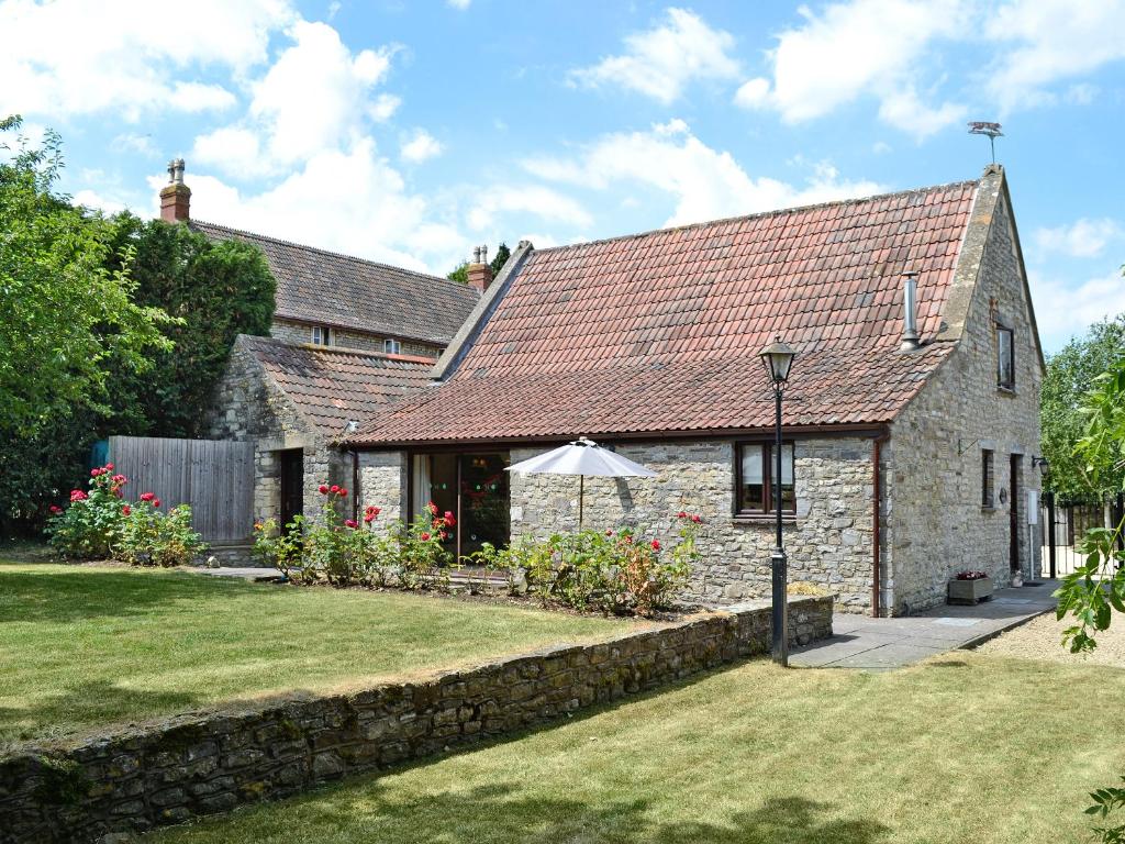 a stone house with an umbrella in a yard at Fox Cottage - E4510 in Chipping Sodbury