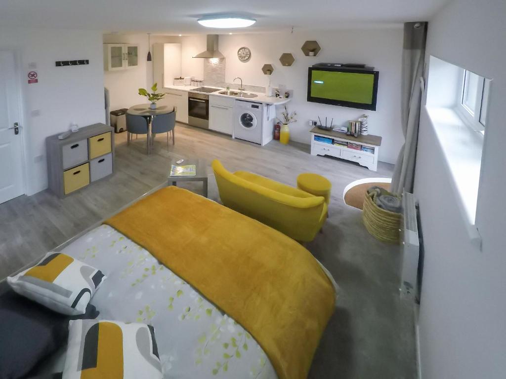 a room with a bed and a kitchen with a tv at The Secret Luxury Apartment in New Romney