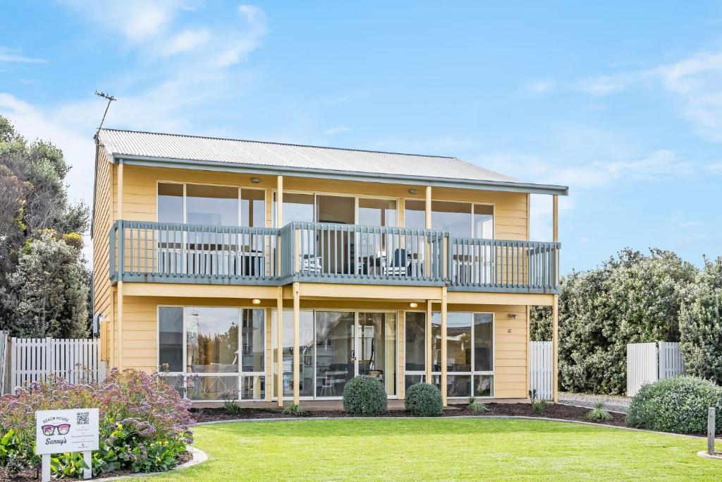 a large yellow house with a balcony at Sunnys Beachhouse - 70 Hargreaves Rd, Middleton in Middleton