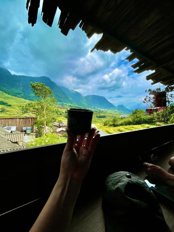 a person holding a cup in front of a window at Sky View hostel in Sapa