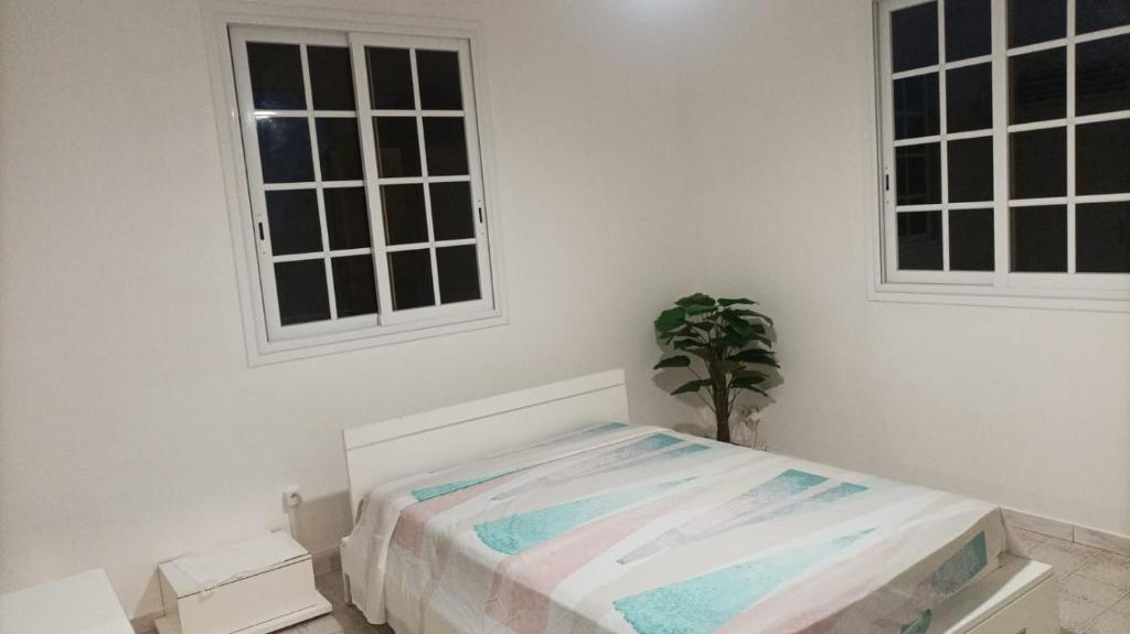 a white bedroom with a bed and two windows at Maison d'hôte Trésor in Sainte-Anne