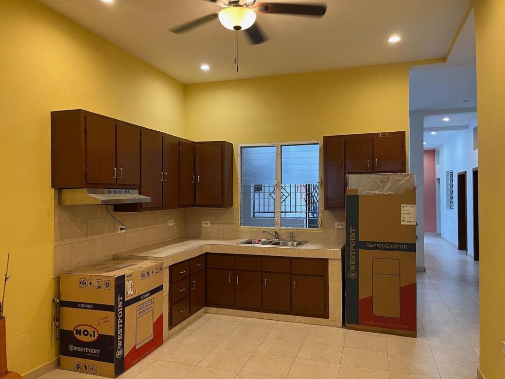 a kitchen with brown cabinets and a ceiling fan at Auberge du Gouverneur, Rue 13-14J, Cap-Haitien, Haiti in Cap-Haïtien