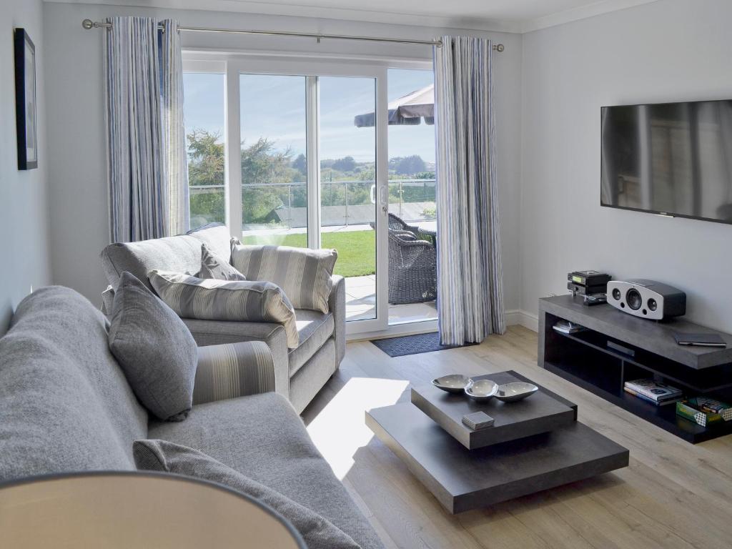 a living room with a couch and a tv at Sand Dunes in Tywardreath