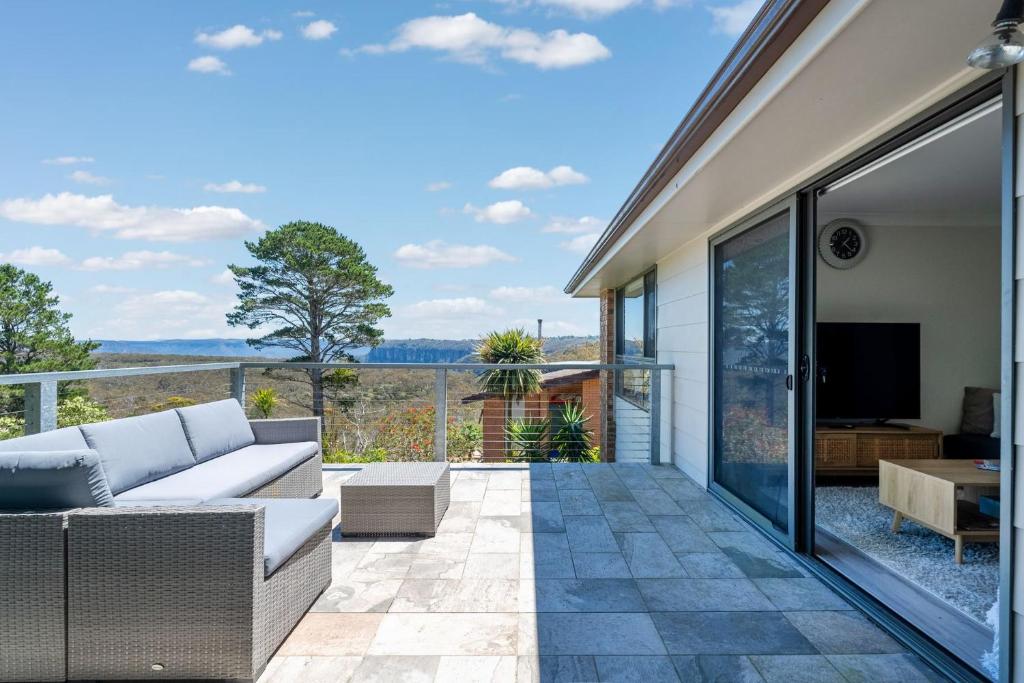 a living room with a couch and a television on a balcony at Misty Haven at Wentworth Falls in Wentworth Falls