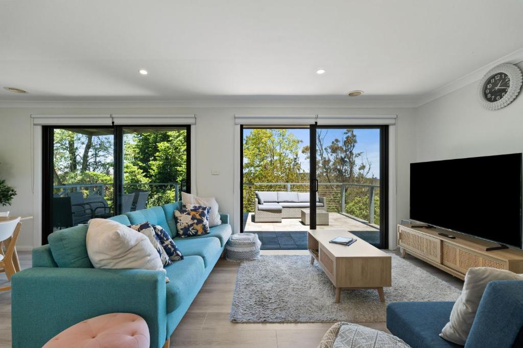 a living room with a blue couch and a flat screen tv at Fern & Maple Lodge Wentworth Falls in Wentworth Falls
