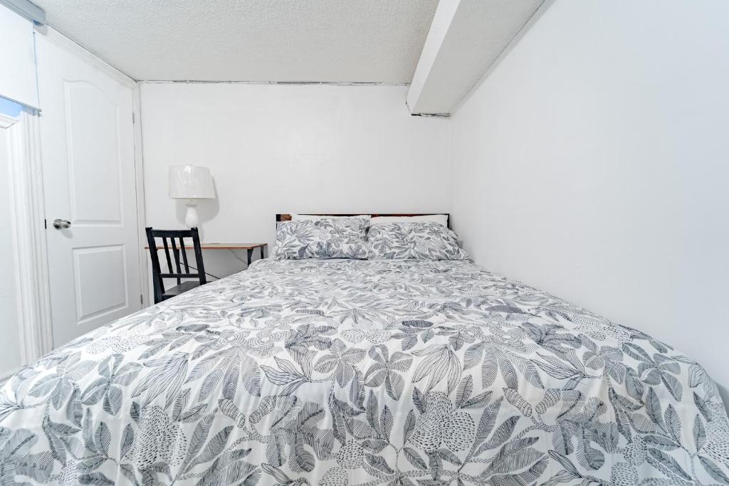 een slaapkamer met een bed met een grijze en witte sprei bij Bright & Spacious 2 Bedroom Apartment Free Wi-Fi, Free Parking, Near Nature Trails in Toronto