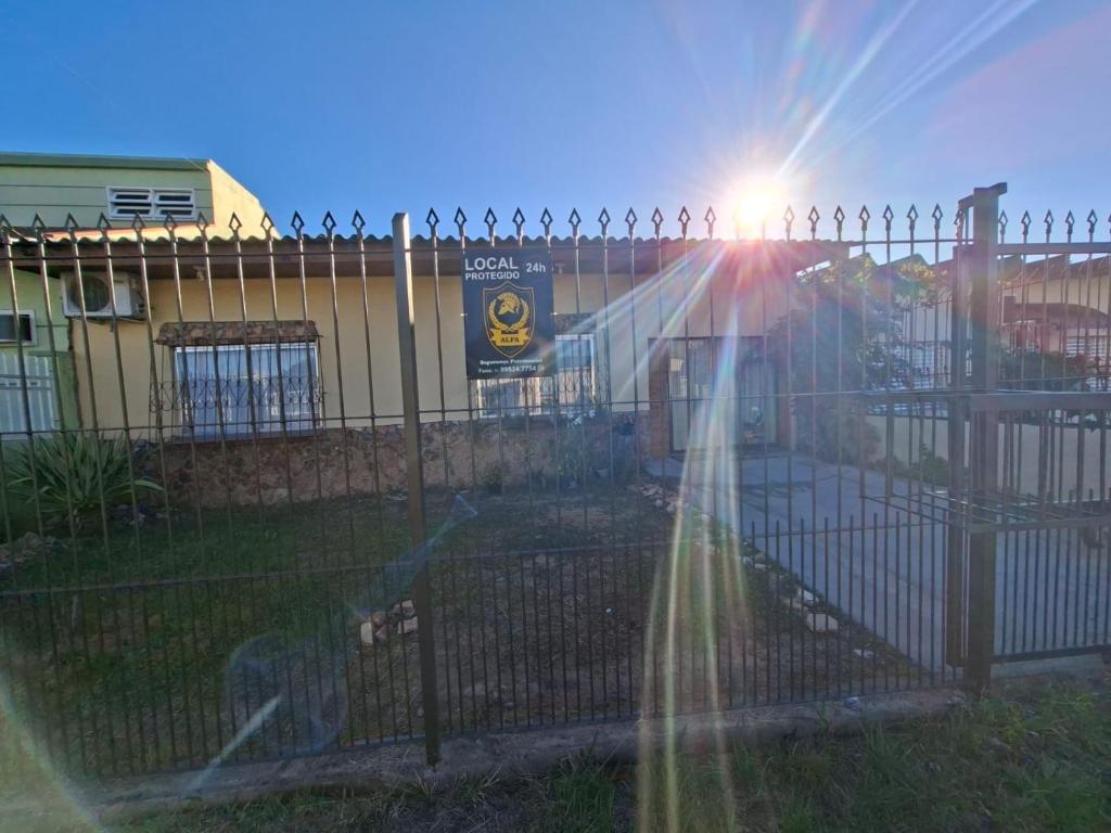 Una recinzione con il sole che splende dietro di essa di Casa reformada com Ar condicionado e Garagem, perto CMPC e BR 116 com Self Check-in a Guaíba