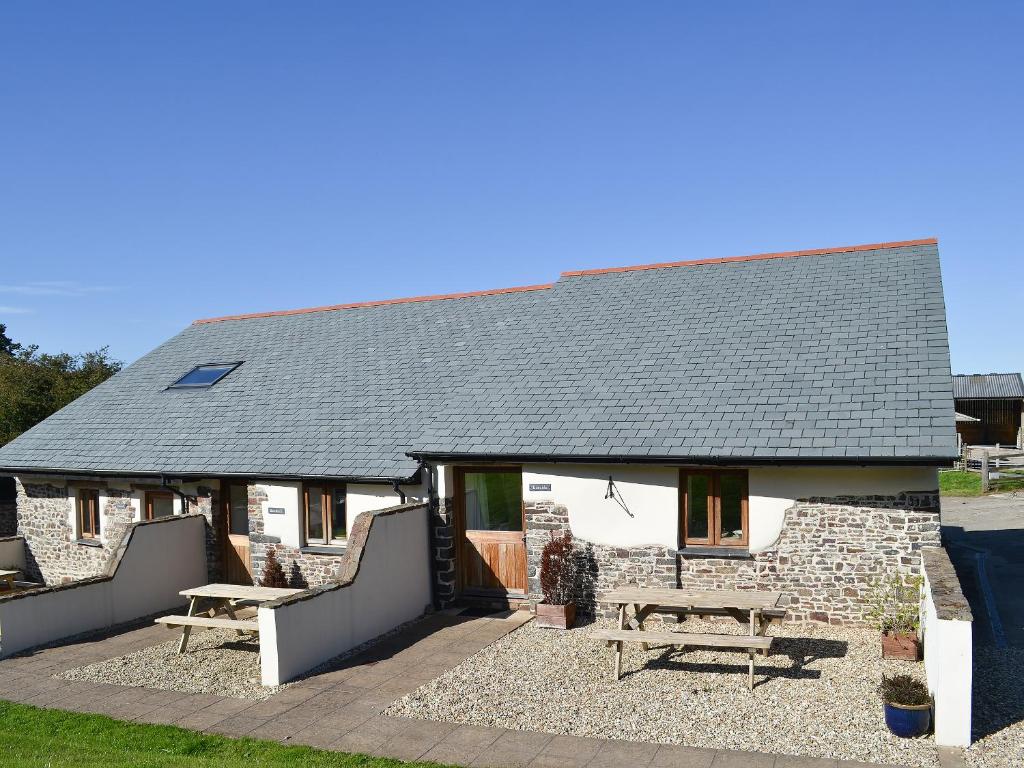 a cottage with a picnic table and a bench at Bramble in Hartland