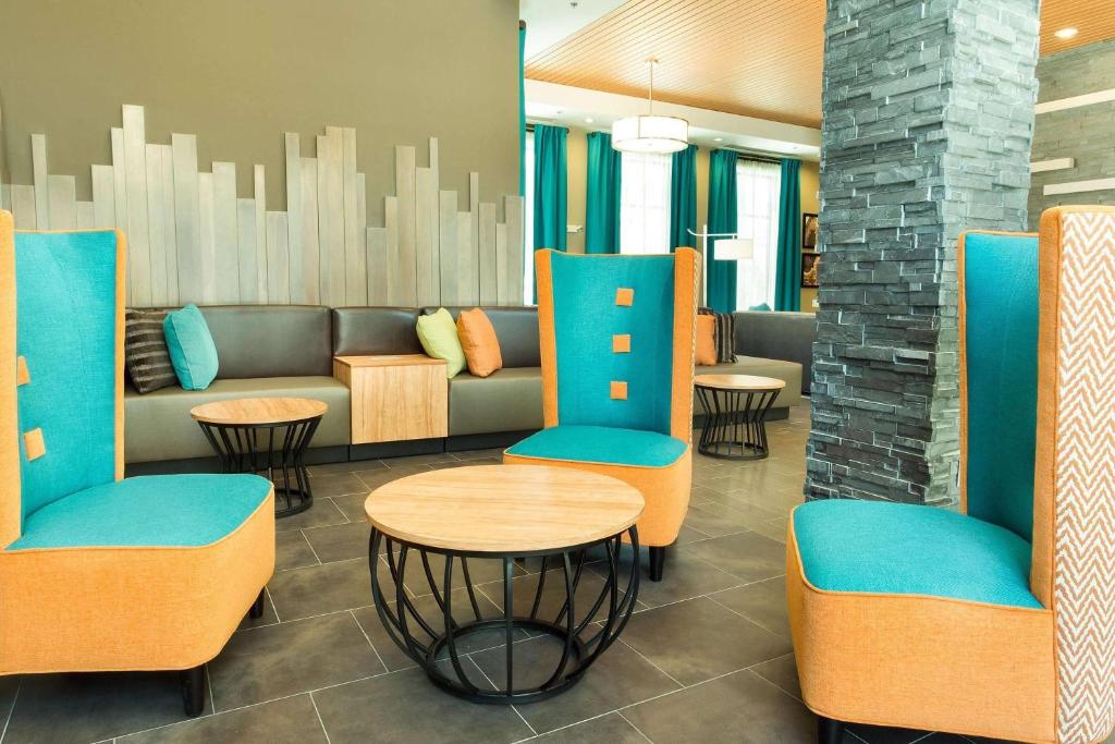 a lobby with a couch and tables and chairs at Heritage Inn & Suites San Antonio Airport, Trademark Wyndham in San Antonio