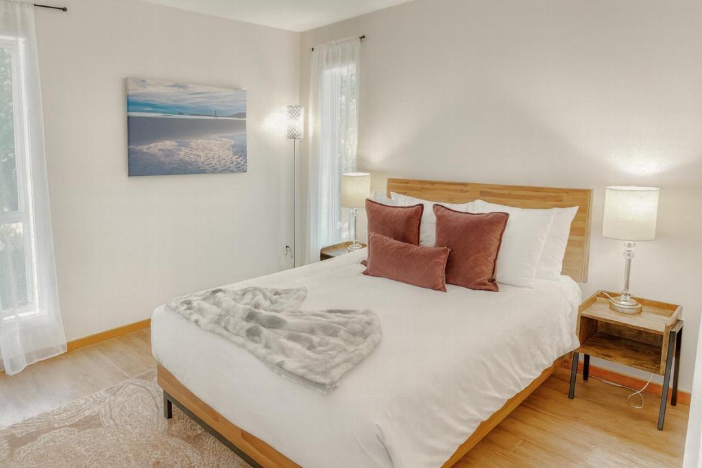 a bedroom with a large white bed with pillows at Tonquin Beach House - EV Charger, Wood Fireplace, Steps from beach in Tofino