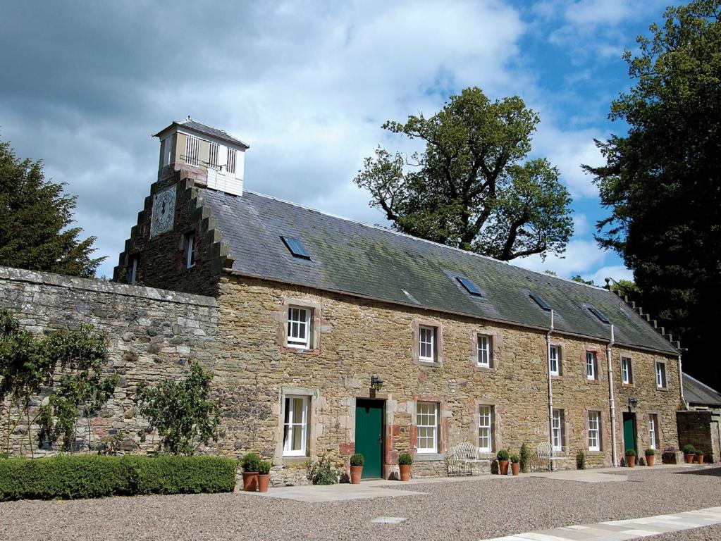 un gran edificio de ladrillo con una torre de reloj en la parte superior en The Clock House, en Smailholm