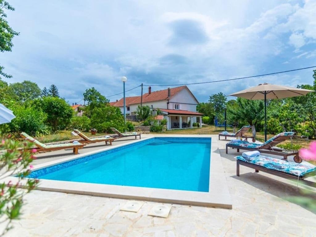 a swimming pool with lounge chairs and an umbrella at Villa Mia with pool in Aračići