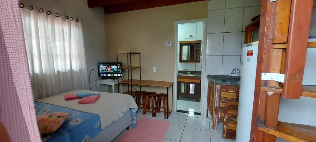 a bedroom with a bed and a kitchen with a refrigerator at Kitinet 06 aconchego, 350 meters from 4 Ilhas in Bombinhas