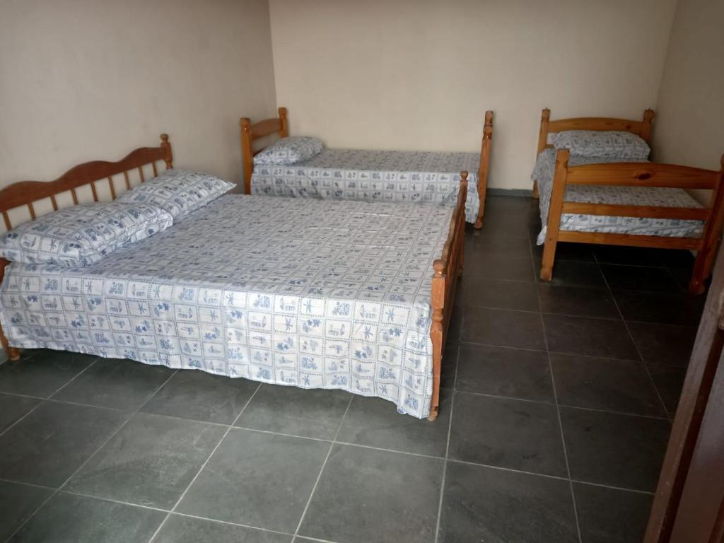 three beds in a room with a tiled floor at Casas em frente ao mar com piscina, churrasqueira in Pontal do Paraná