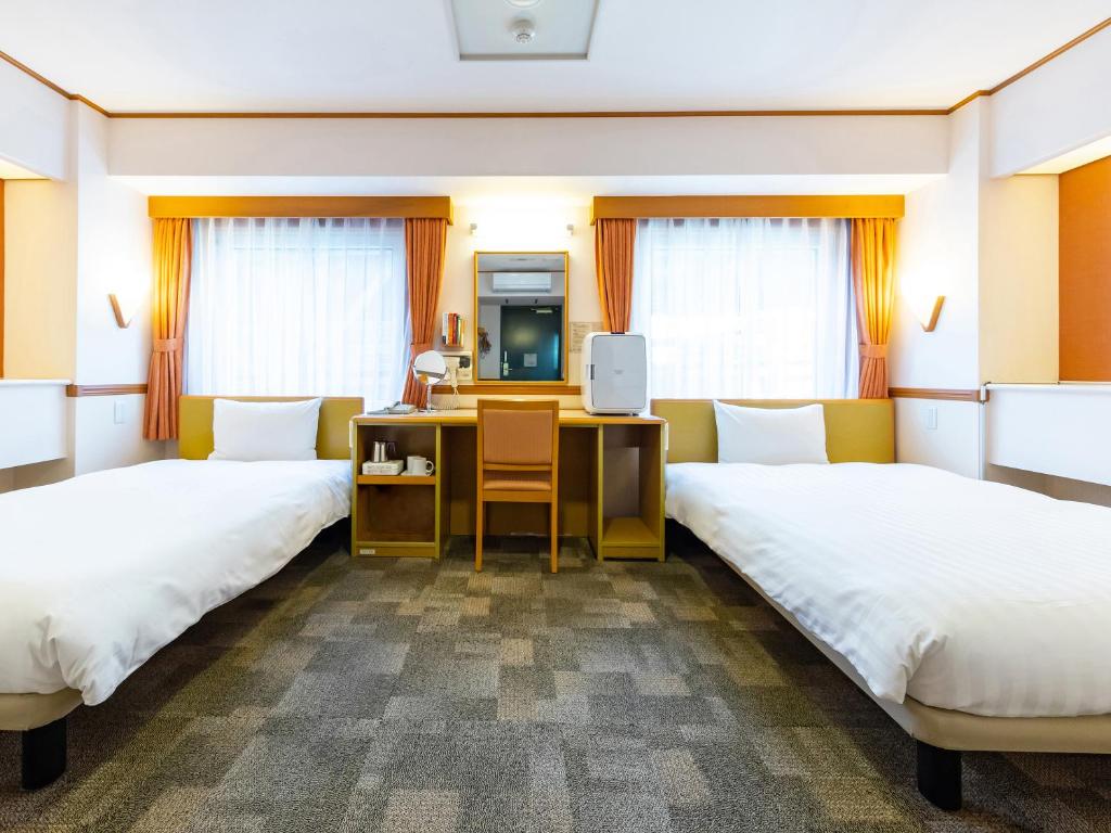a hotel room with two beds and a desk at Toyoko Inn Hokkaido Kitami Ekimae in Kitami