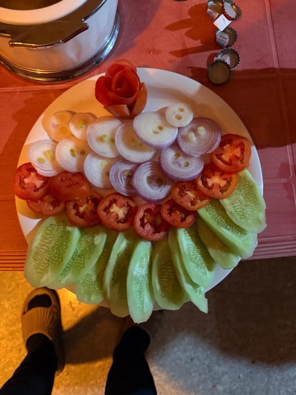 un plato de comida con tomates y cebollas en una mesa en Nirvana River Nest, en Sainj