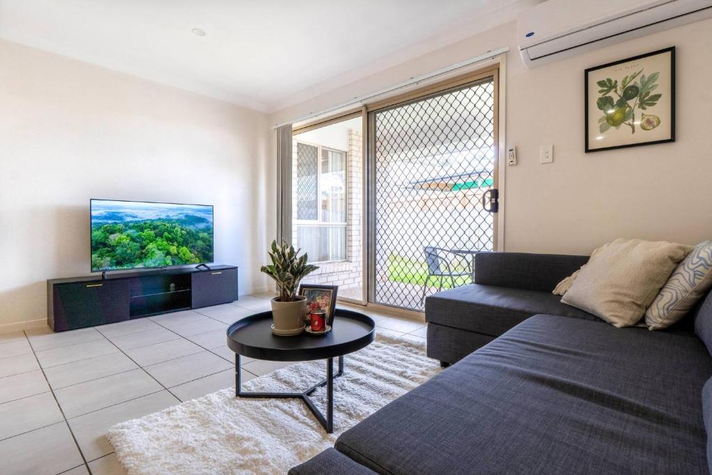 a living room with a couch and a tv at Bright & Cozy 2BR Duplex near Logan Central Comforts in Marsden