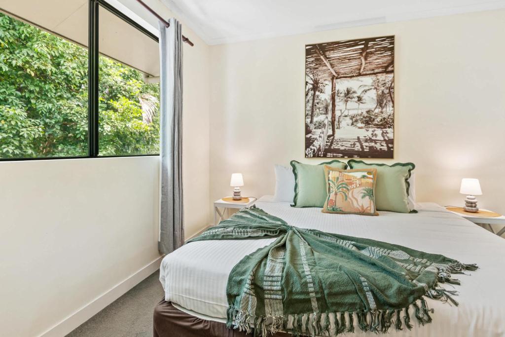 a bedroom with a bed and two windows at Palm Cove Studio Pools Spa Bar in Palm Beach