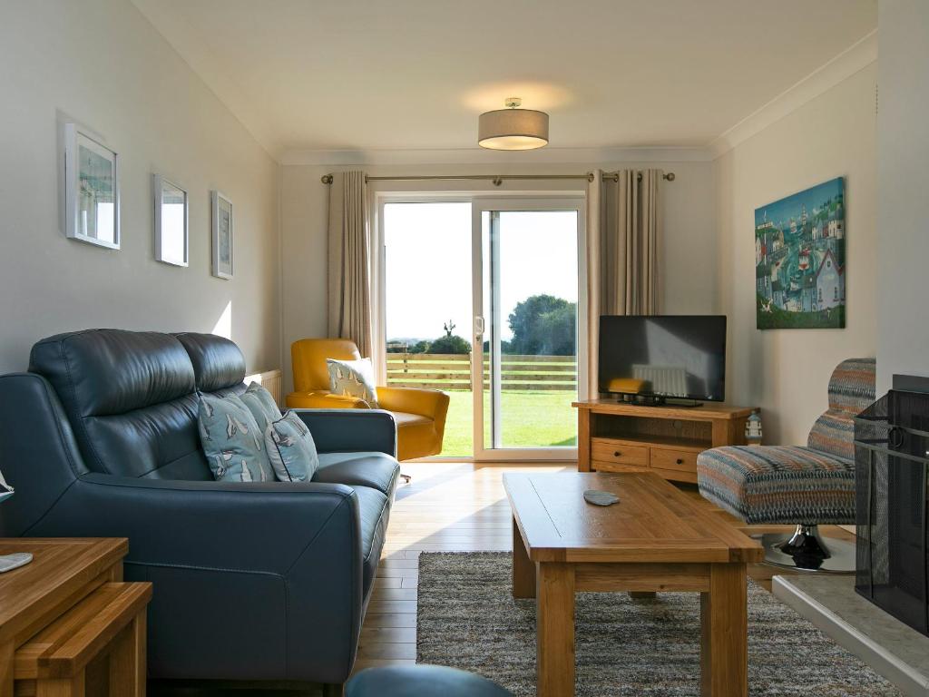 a living room with a blue couch and a tv at Headlands House - Uk6739 in Lydstep