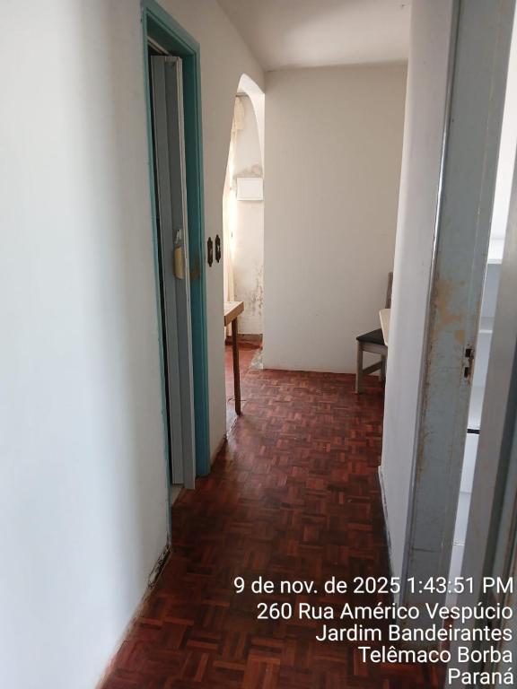 een gang met een groene deur en een rode bakstenen vloer bij Kitnet na Band in Telêmaco Borba