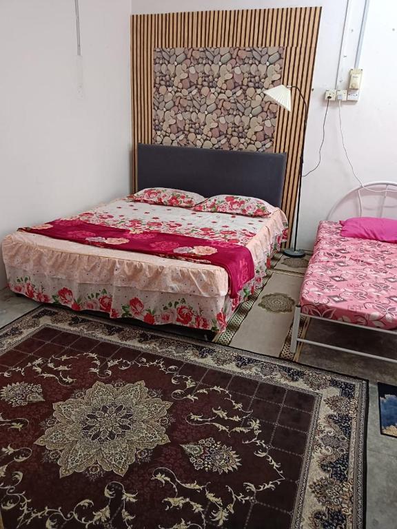 a bedroom with two beds and a rug at Roomstay Ummi in Macang