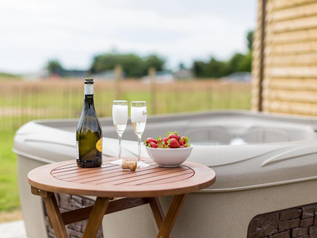 a bottle of wine and two glasses on a table next to a tub at Olive in Wootton Bridge