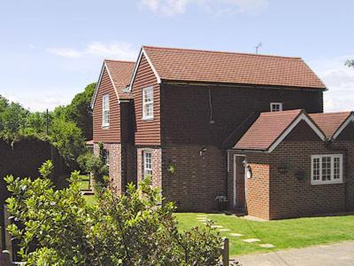 a brown brick house with a brown roof at Holly Cottage in Pett