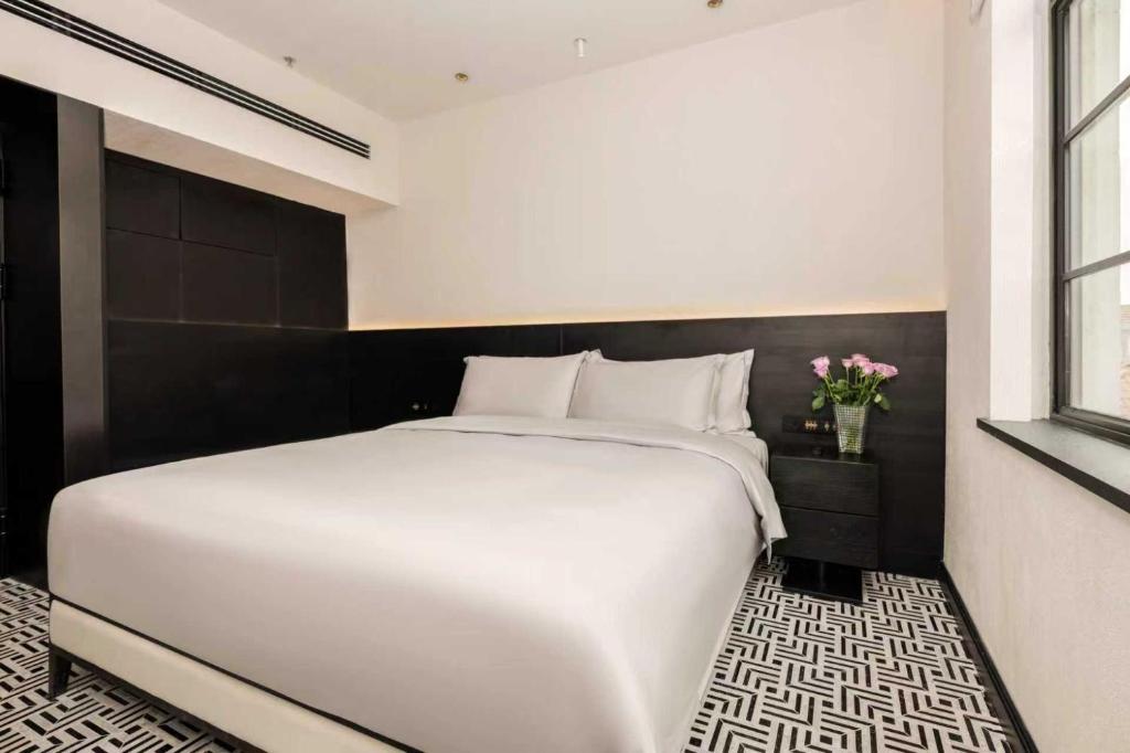 a bedroom with a large white bed and a vase of flowers at 烟台朝阳文保艺术酒店 in Yantai