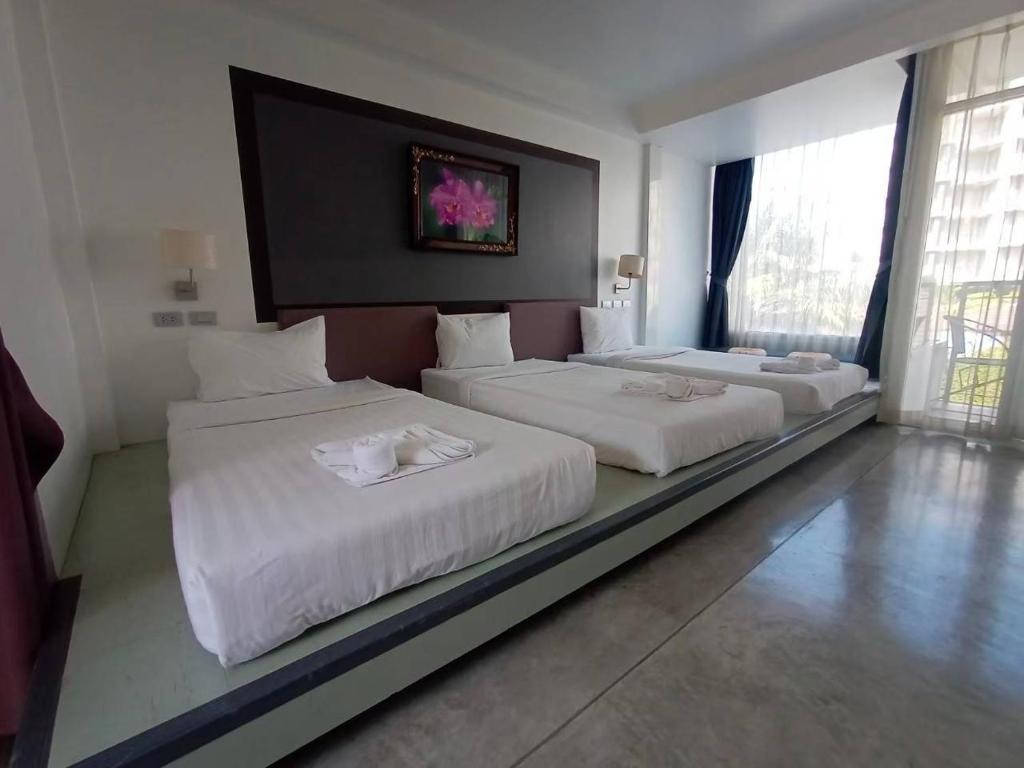 a hotel room with two beds with white sheets at Sunset Serenity Jomtien Resort in Na Jomtien