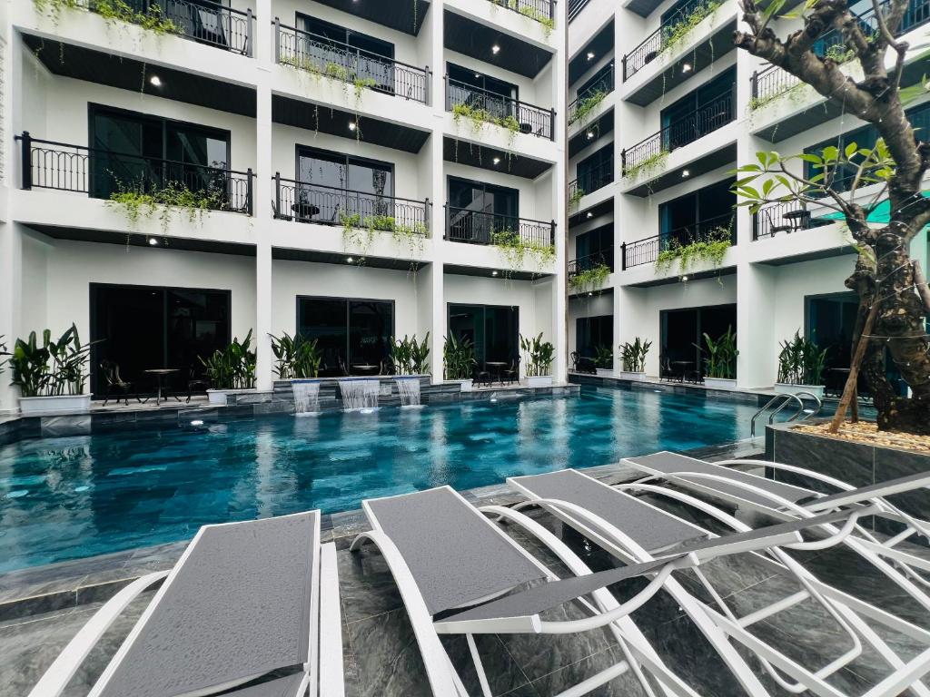 a swimming pool with lounge chairs in front of a building at The Green Hotel Vientiane in Vientiane