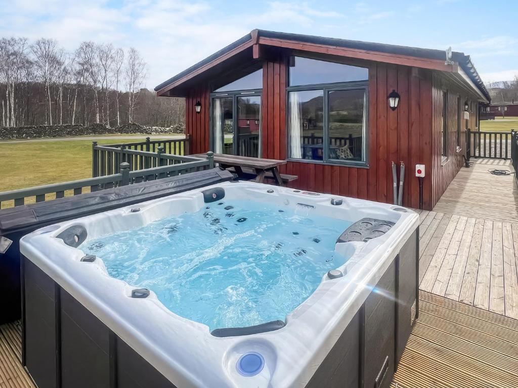 a hot tub on a deck next to a house at Cruachan in Etteridge