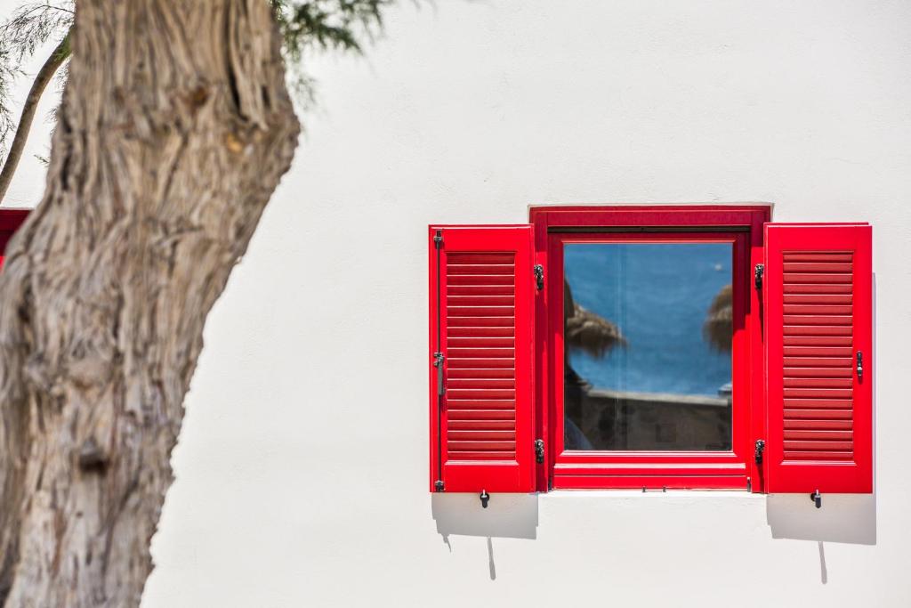 a red window on the side of a building with a tree at Sunhaus in Perissa