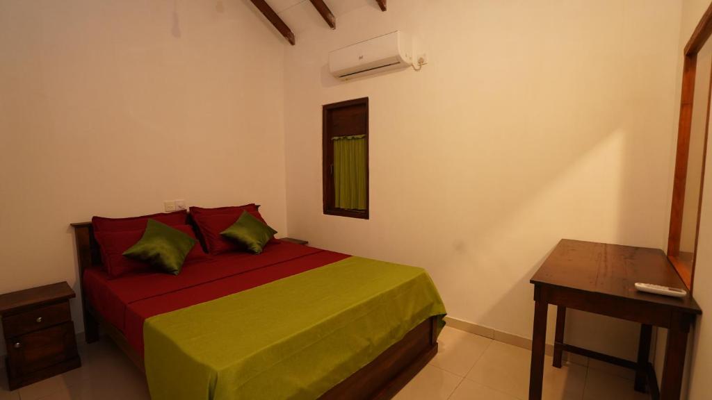 a bedroom with a bed with green and red sheets at New Morning Hikkaduwa in Hikkaduwa