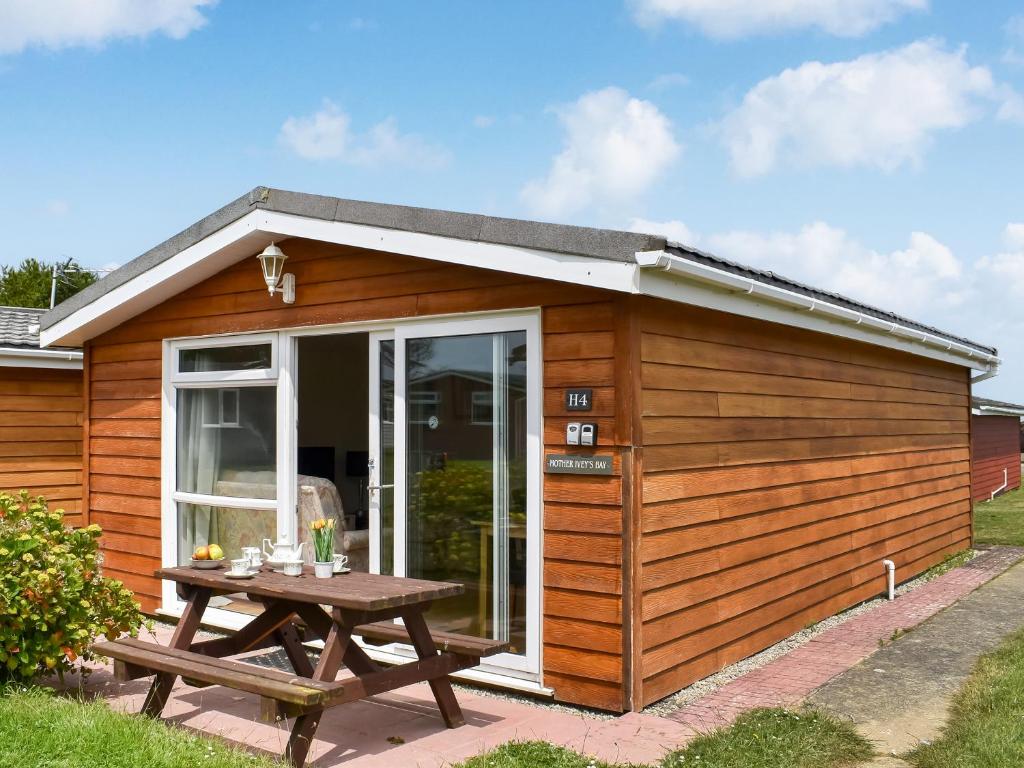 ein Holzschuppen mit einem Picknicktisch davor in der Unterkunft Mother Ivy's Bay - Uk47553 in Saint Merryn