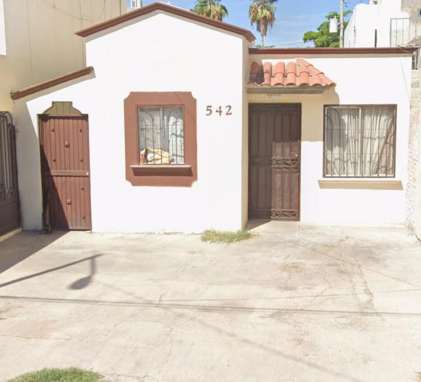 a white house with two gates and a driveway at Casa amplia y céntrica cerca de Laguna del Náinari in Ciudad Obregón