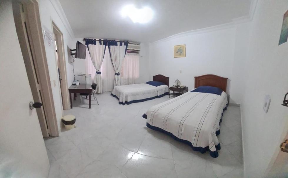 Un dormitorio con dos camas y un escritorio y una mesa. en Hotel Lord by Croma, en Cúcuta