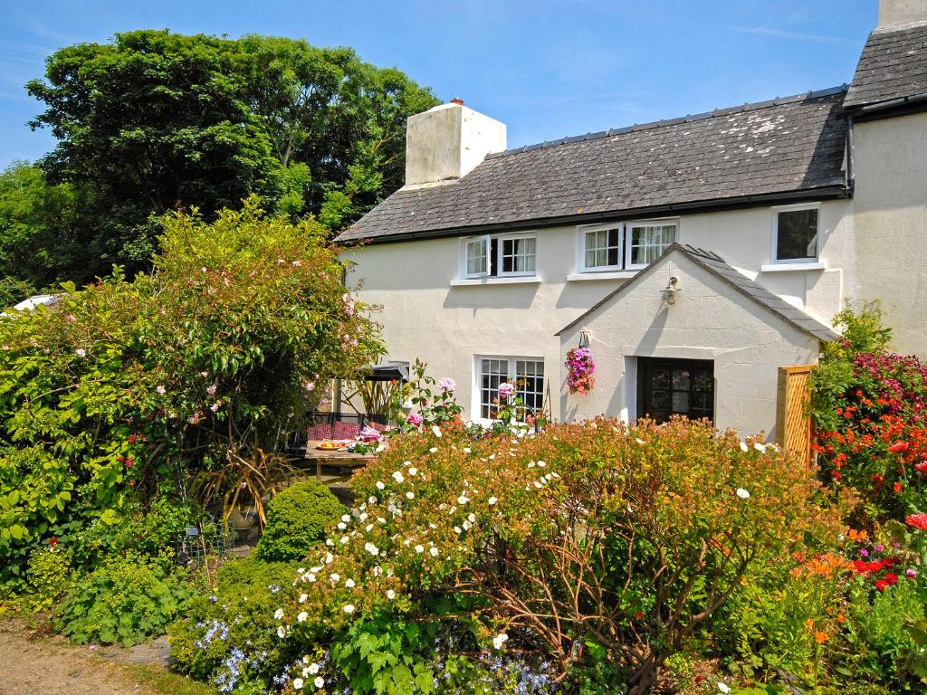 a white house with flowers in a garden at Llys Isaf in Saint Nicholas