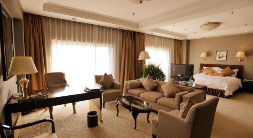 een grote woonkamer met een bed en een bank bij Jinjiang Hotel Qianan in Qian'an