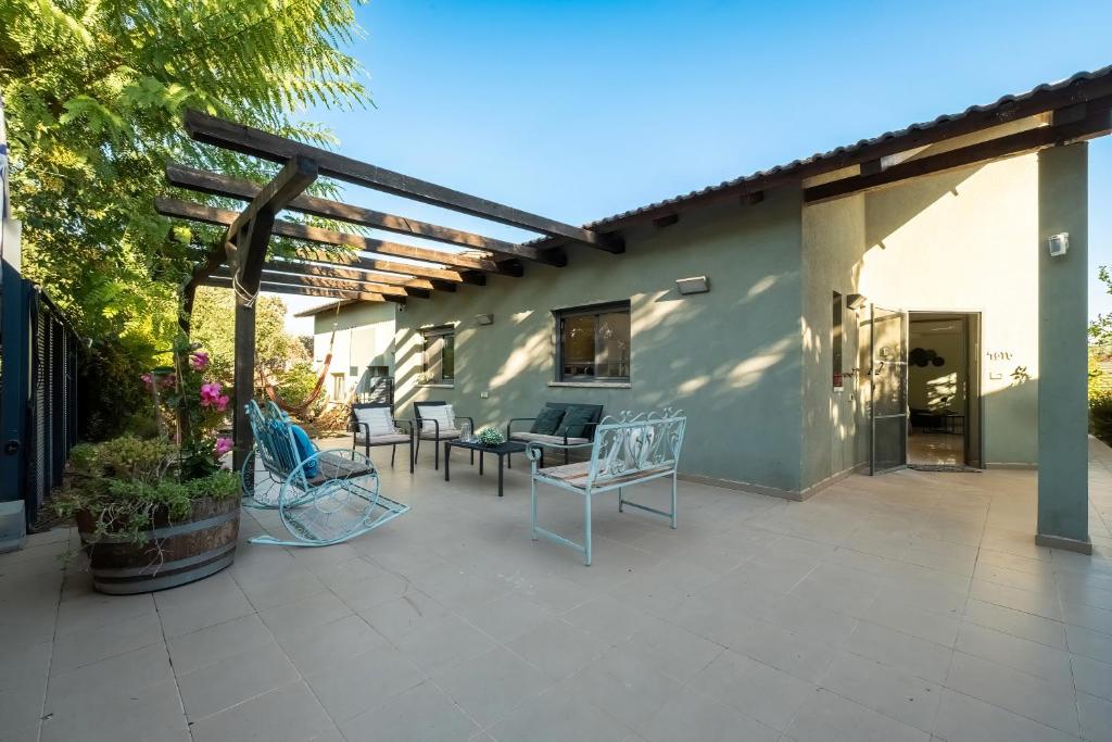 een patio met stoelen en tafels en een gebouw bij Tranquil Galilee Countryside Retreat by Sea N' Rent in Tefahot
